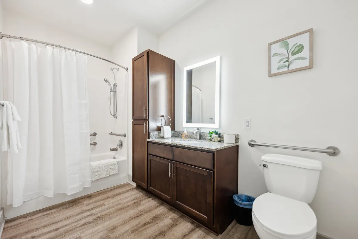 A beautifully styled bathroom with a bright vanity, large mirror, and an inviting bathtub with a shower curtain. The space feels fresh and restful, suggesting moments of calm, whether starting the day with a morning ritual or unwinding with a bath in the evening.